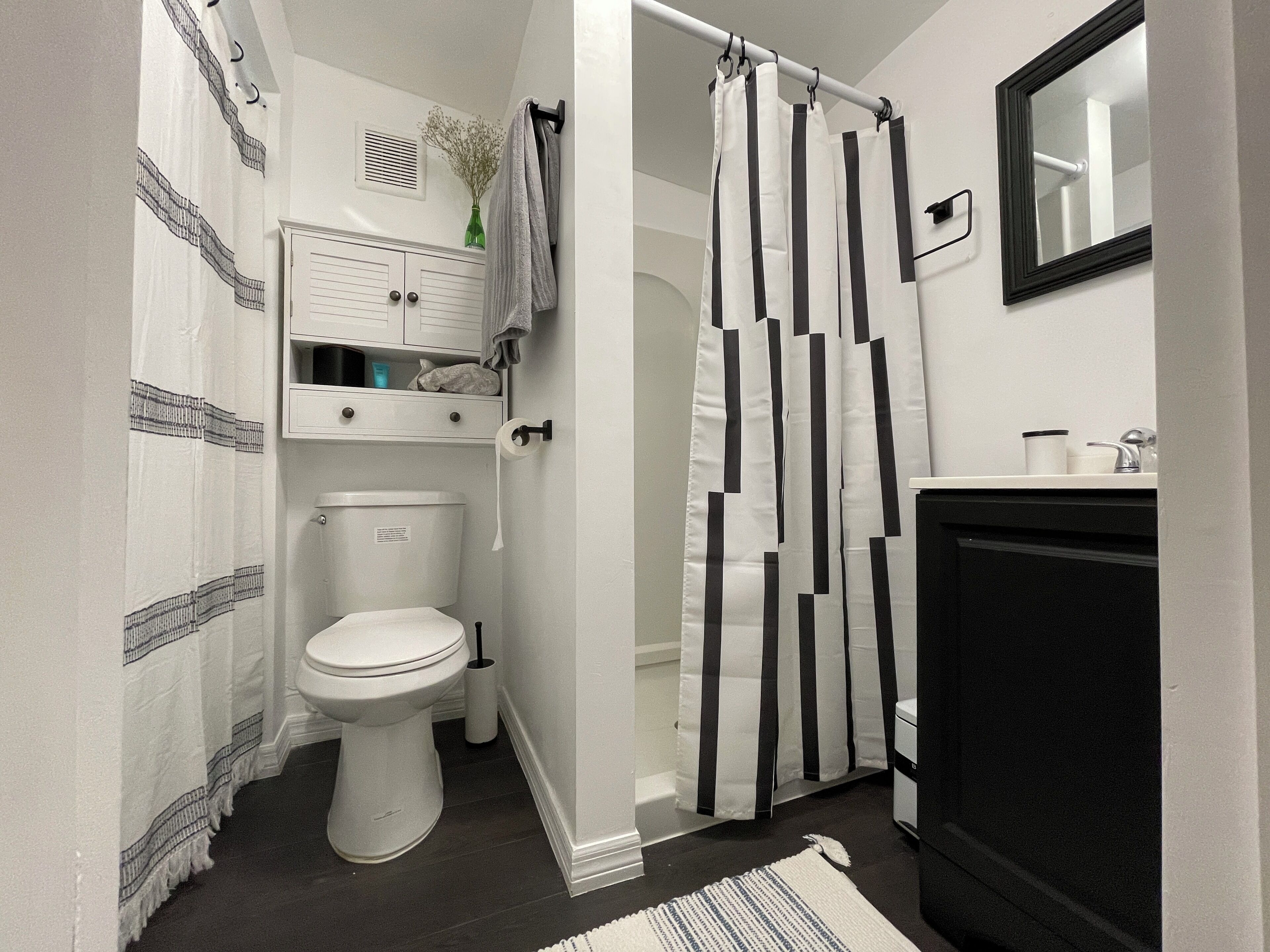 Un baño con inodoro, cortina de ducha, espejo y lavamanos.