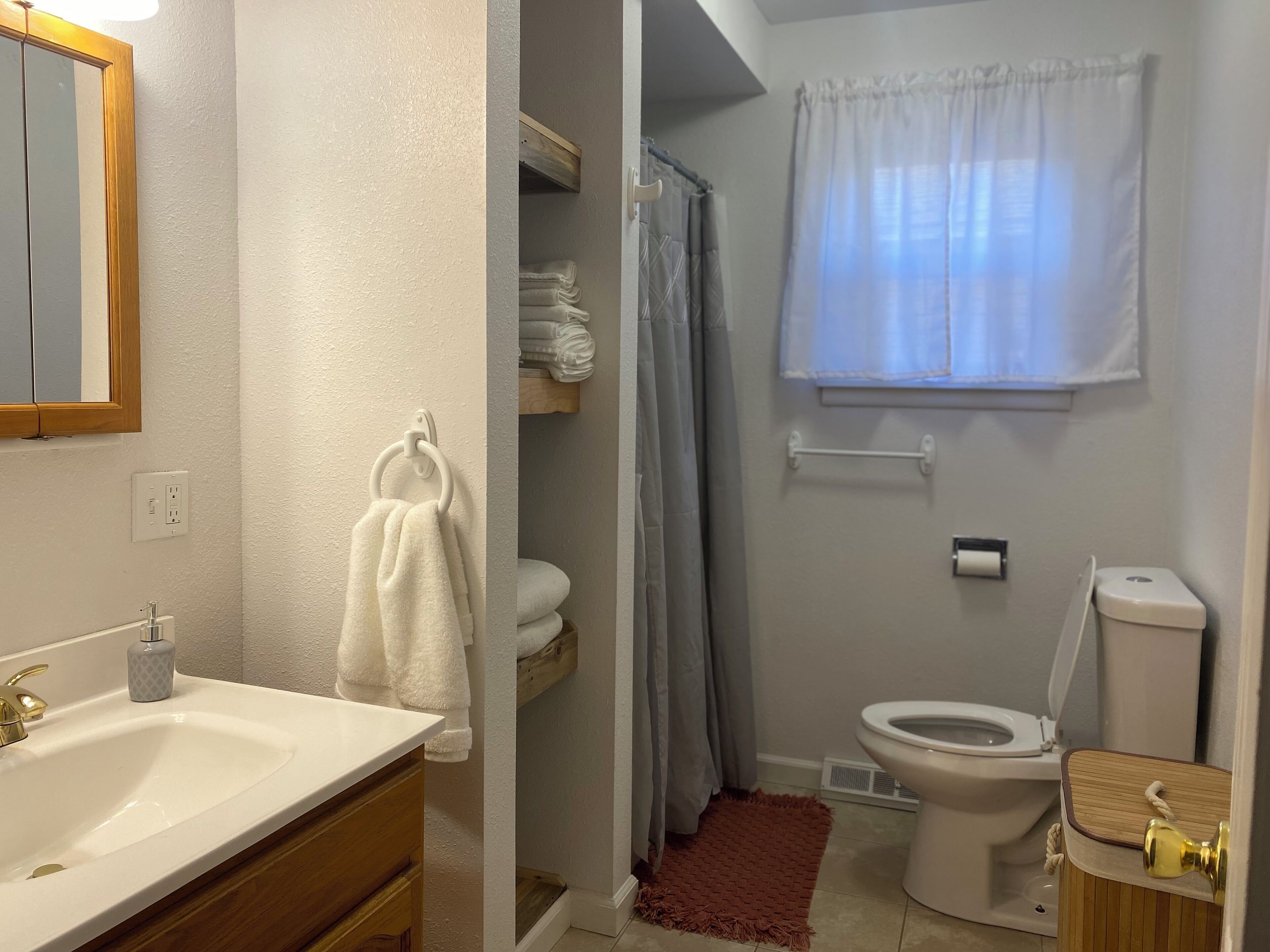A bathroom with a sink, toilet, and shower area.