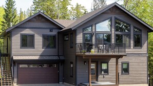 A two-story house with a garage, a balcony, and a large window. - Ski In to your Private Hot Tub. Foosball Table. (Fernie)