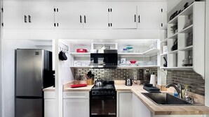 Una cocina moderna con armarios blancos, un refrigerador de acero inoxidable, un microondas, una estufa y un lavaplatos.