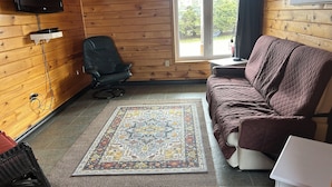 Una stanza accogliente con arredi in legno, un divano, una poltrona, un televisore e un tappeto decorato.