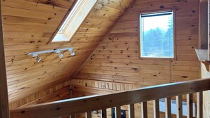 Un interno in legno con soffitto spiovente, una finestra e una ringhiera in metallo.