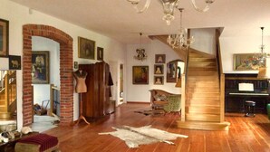 Un salon spacieux doté de planchers en bois franc, d’un escalier et d’un piano.