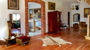 Un salon spacieux doté d’un parquet en bois, d’une arche en briques et d’un grand tableau.