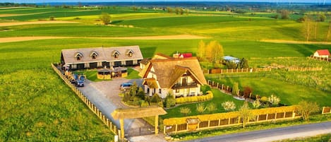 Une propriété rurale comprenant une grande maison, une grange et de vastes champs verdoyants.