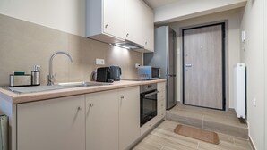 A modern kitchen with a sink, stove, microwave, and refrigerator. - Ilisia 2 person apartment by MPS (Athina)