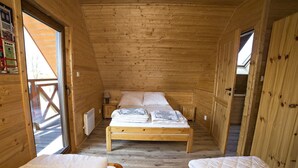 Une chambre dans une cabane en bois, avec un lit simple et deux petits lits.