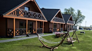 Une rangée de chalets en bois dotés de balcons, une pelouse verdoyante et un hamac.