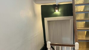 A staircase with a wooden handrail and white balusters, leading to a landing with a white door and a green wall.
