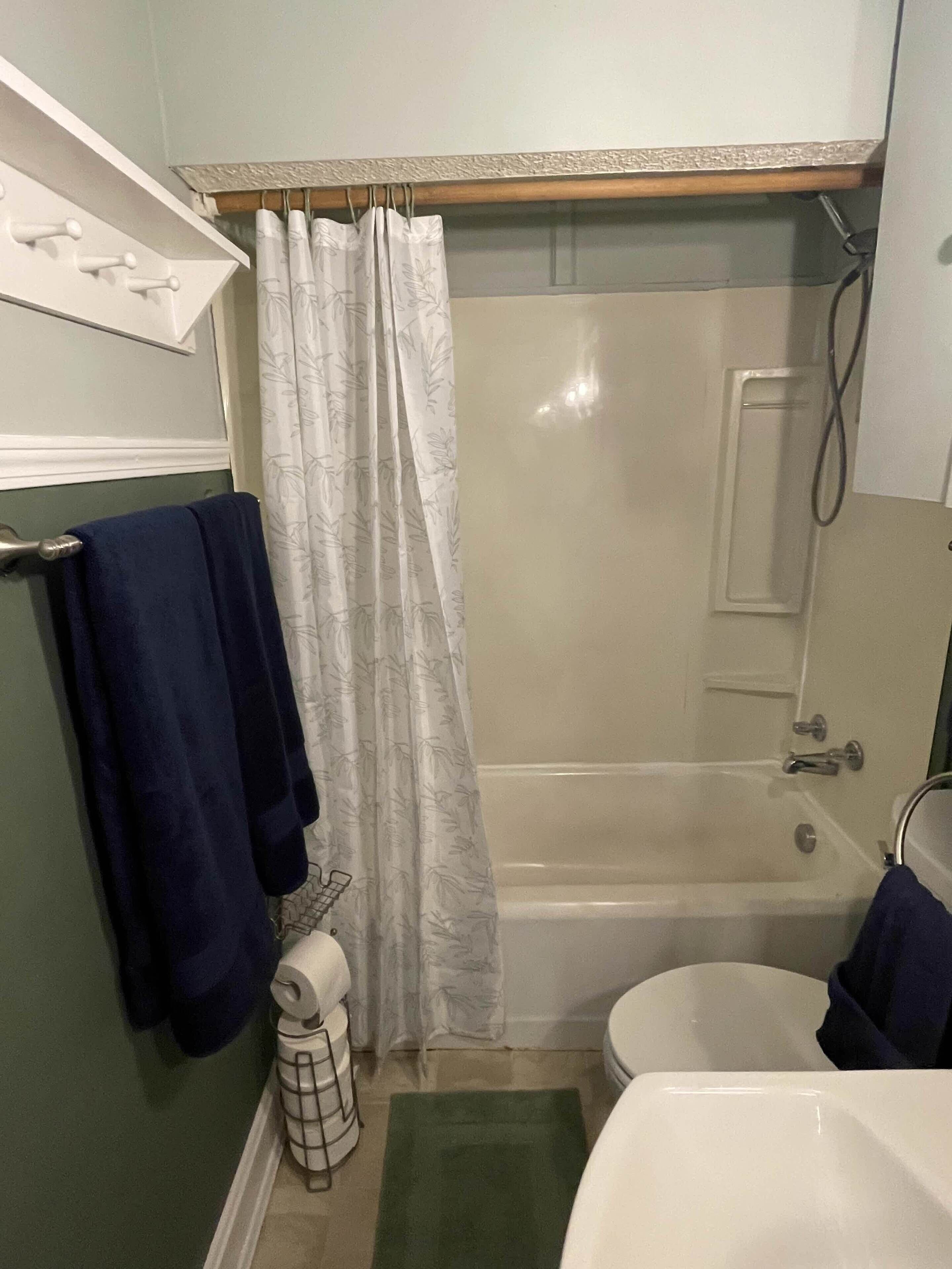 A bathroom with a bathtub, toilet, and shower curtain.