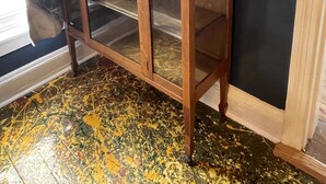 A wooden cabinet with glass doors against a dark wall.