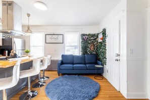 A modern kitchen with a bar area, a blue sofa, and a decorative wall. - Fairfield Whole House (Fairfield)