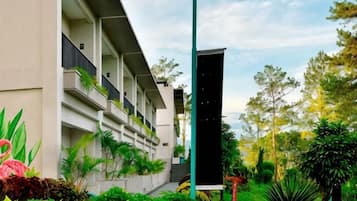 Un hôtel moderne à l’architecture imposante, doté d’un jardin bien entretenu et offrant une vue sur un ciel dégagé.