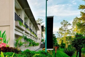 A modern hotel with a multi-story structure, a well-maintained garden, and a clear sky. - The Balcone Suites & Resort (Gadut)
