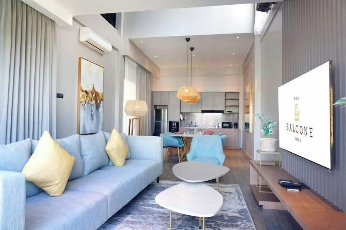 Un salon moderne avec un canapé, une table basse et, au fond, un coin repas.