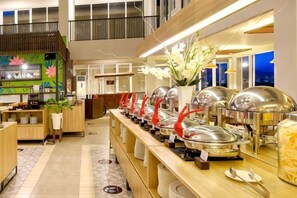A buffet area with multiple food stations, a reception desk, and a decorative plant. - The Balcone Suites & Resort (Gadut)
