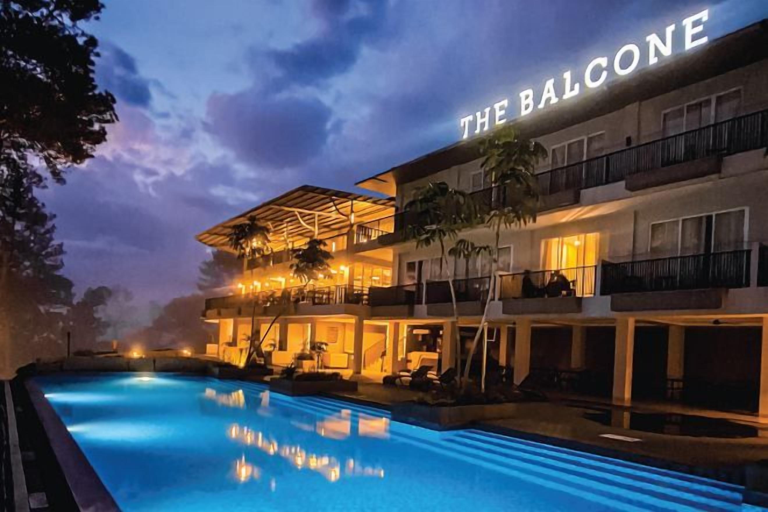 A hotel with a pool, outdoor seating, and a balcony.