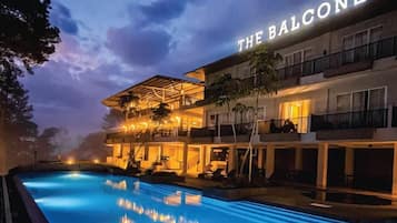 A hotel with a pool, outdoor seating, and a balcony.