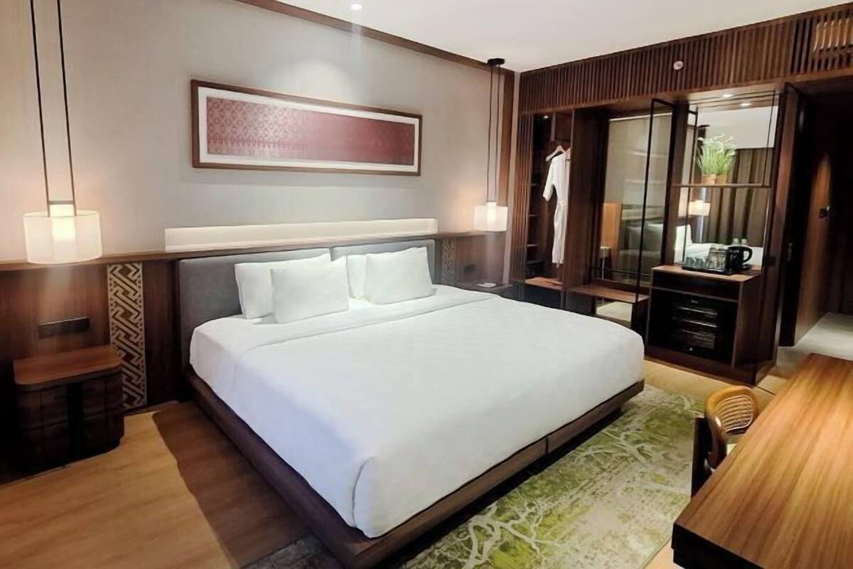 Une chambre d’hôtel avec un grand lit, des tables de chevet, une armoire et un bureau avec une chaise.