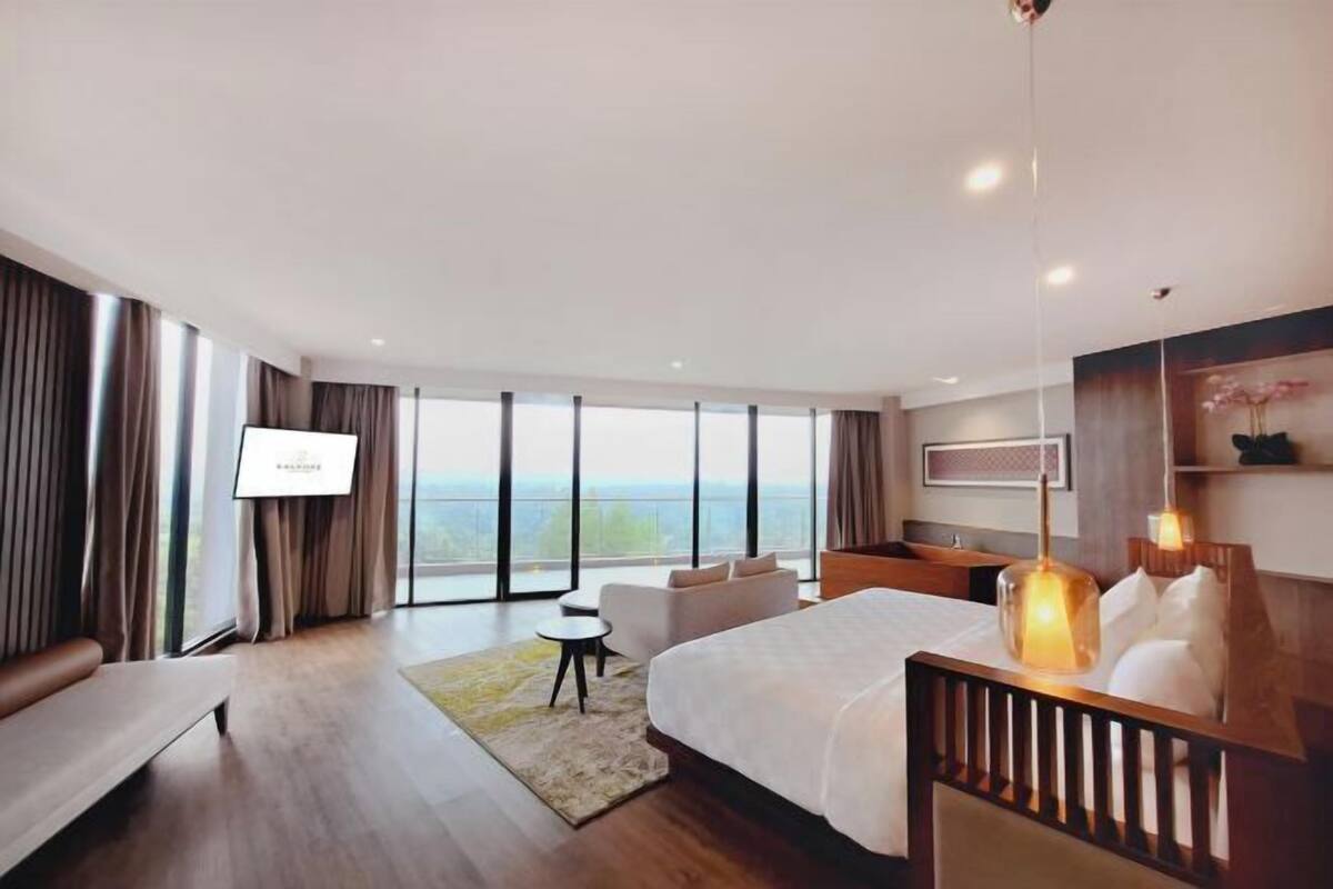 Une chambre d’hôtel moderne dotée d’un grand lit, d’un coin salon, d’une télévision et offrant une vue sur l’extérieur.