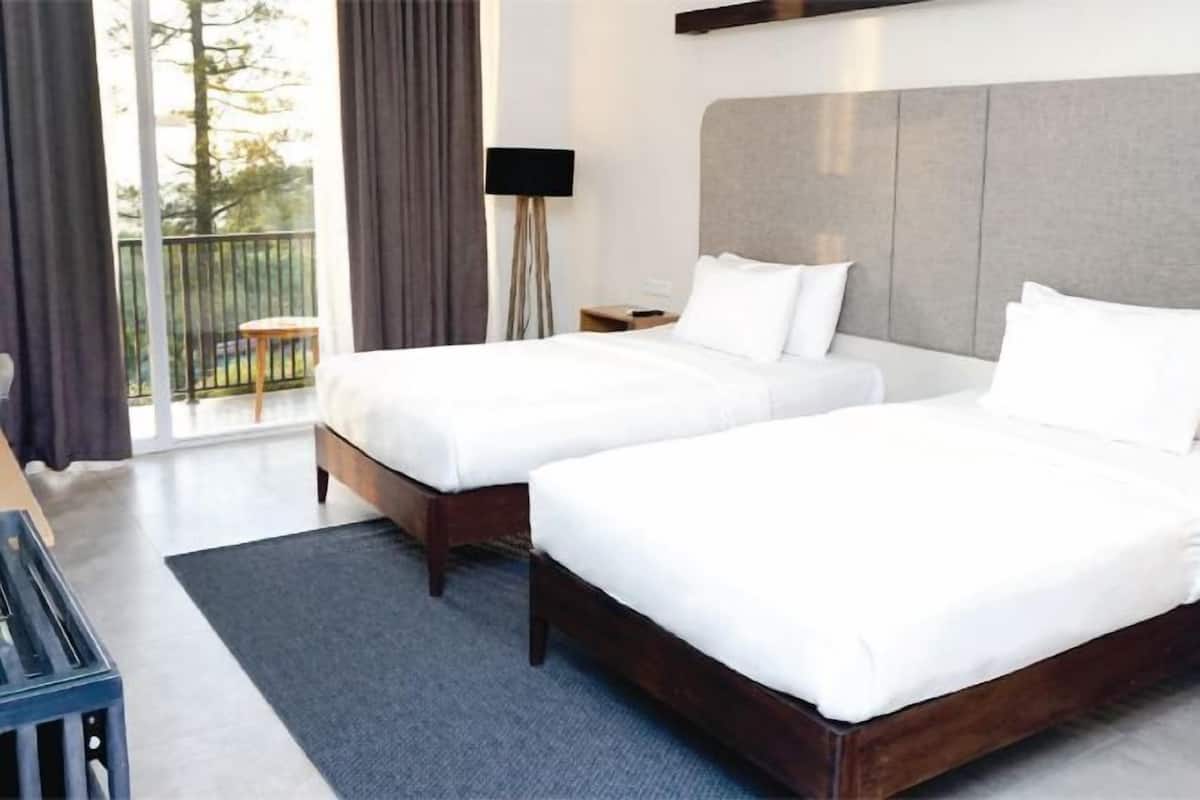 Une chambre d’hôtel avec deux lits, un balcon, un bureau et une lampe.