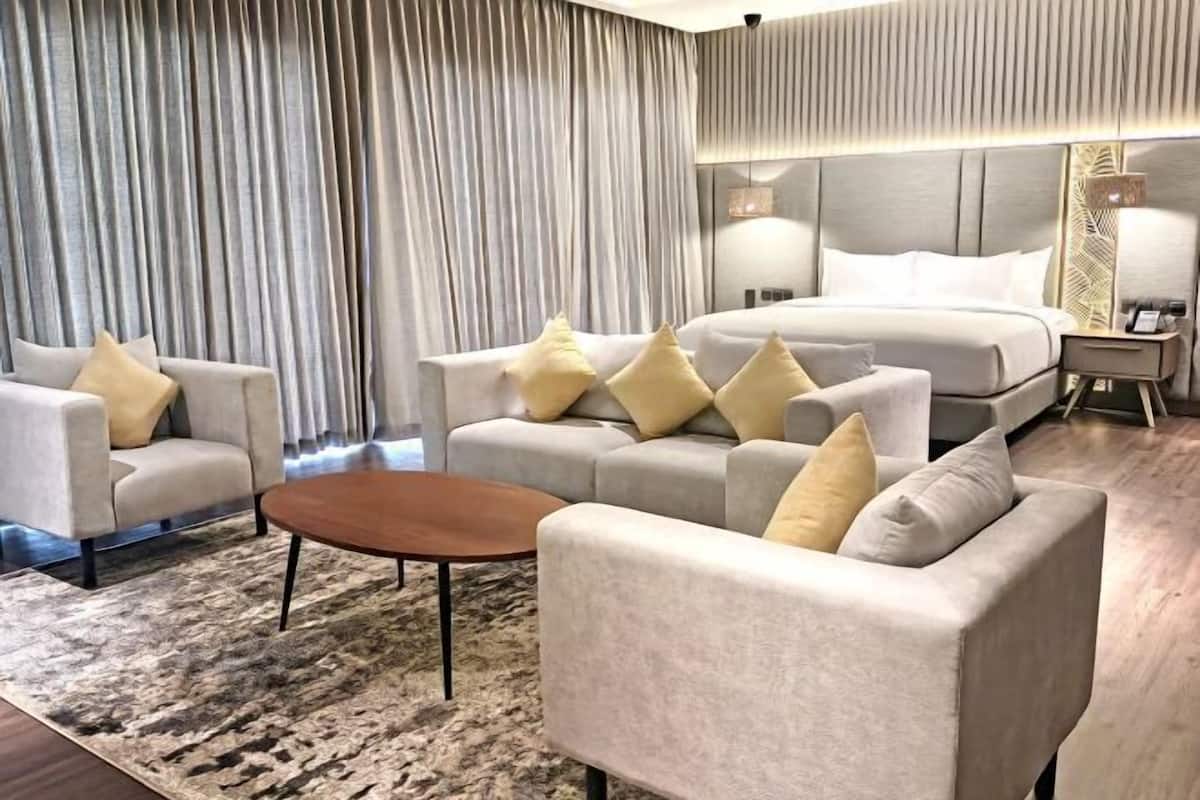 Une chambre d’hôtel moderne avec un grand lit, deux canapés, une table basse et une table de chevet.