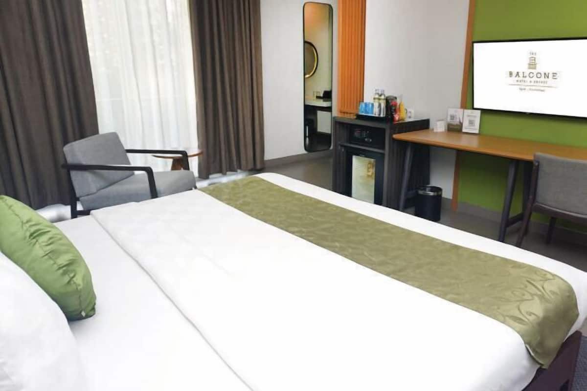 Une chambre d’hôtel équipée d’un lit, d’un bureau, d’une chaise et d’un écran de télévision affichant le nom de l’hôtel.