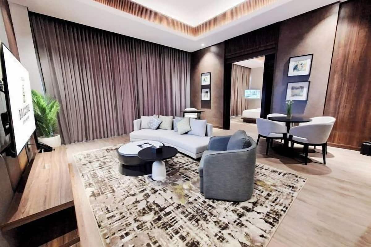 Un salon moderne avec un canapé, des fauteuils, une table basse et un téléviseur.