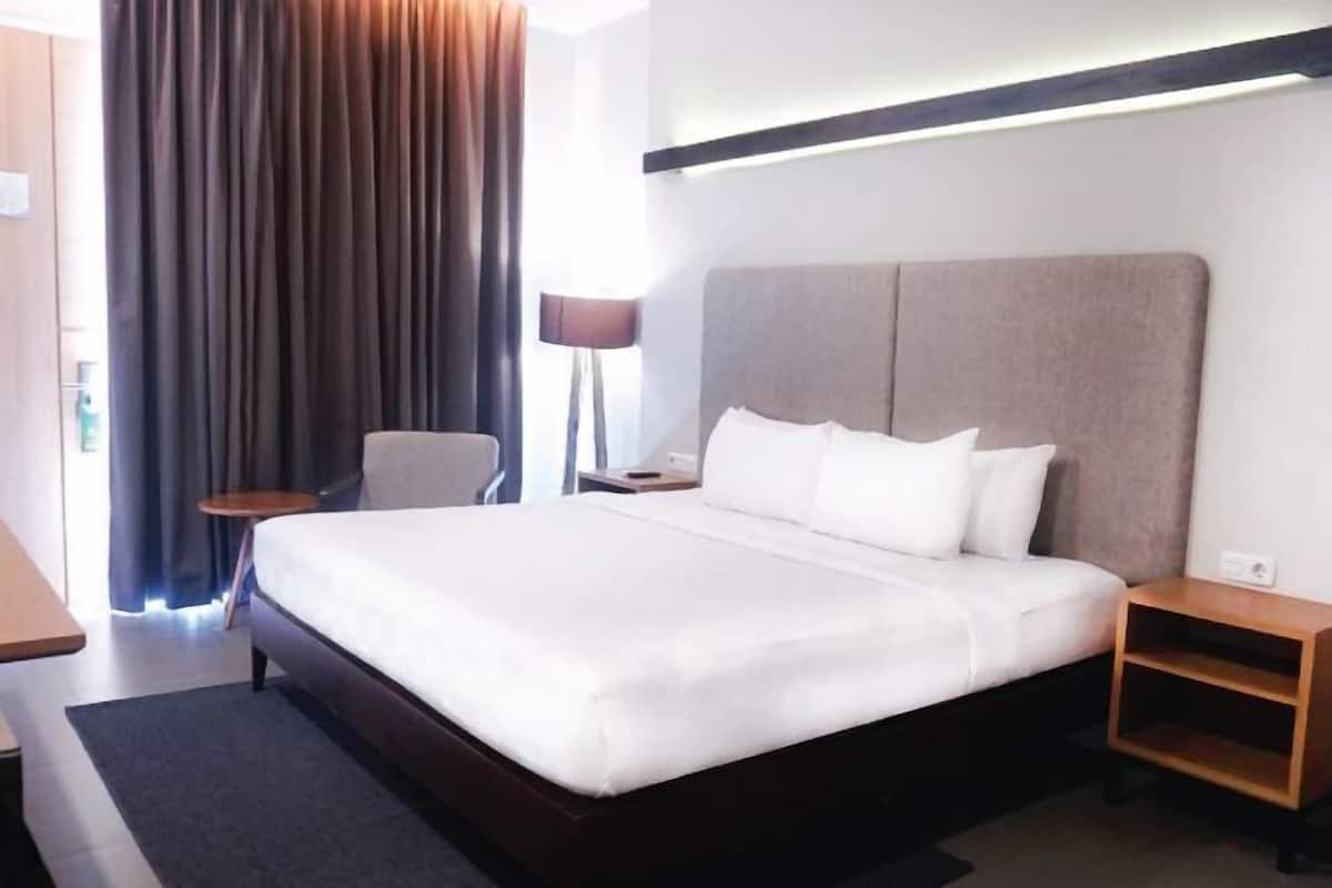 Une chambre d’hôtel avec un grand lit, une table de chevet, une chaise et une lampe.