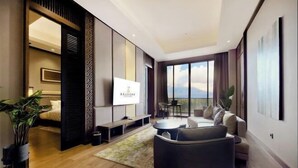 A modern living room with a sofa, a TV, and a balcony with a view. - The Balcone Suites & Resort (Gadut)