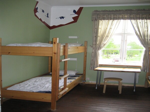 A bunk bed room with a window and a desk.
