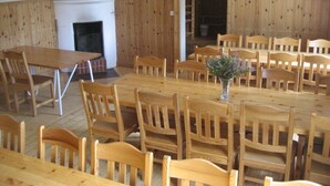 Un espace repas avec des tables et des chaises en bois, une cheminée et des tableaux encadrés aux murs.