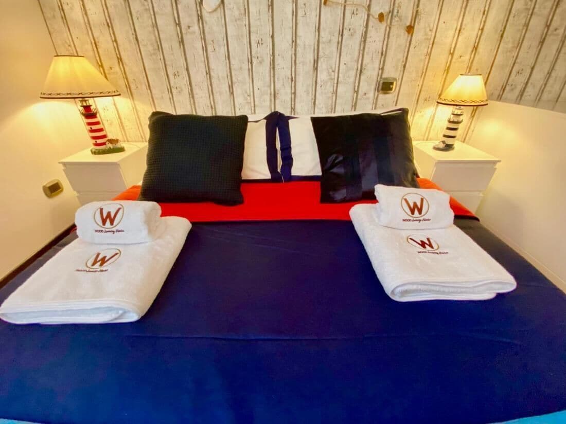 Een hotelkamer met een bed, kussens en handdoeken met een logo.