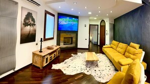 Una sala de estar moderna con un sofá amarillo, una mesa de centro de madera, una chimenea y un televisor de pantalla plana montado en la pared.