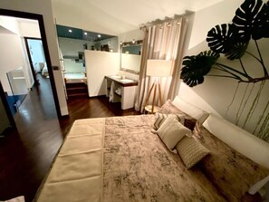 A hotel room with a bed, a desk, a bathroom, and a staircase.