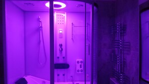 A modern, glass-walled steam room with a control panel, a showerhead, and a seating area. - Your Home In Trastevere (Roma)