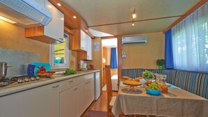 A compact RV kitchen with a dining area, including a table set for breakfast.