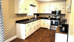 Une cuisine avec des armoires blanches, un plan de travail noir et un plancher en bois.