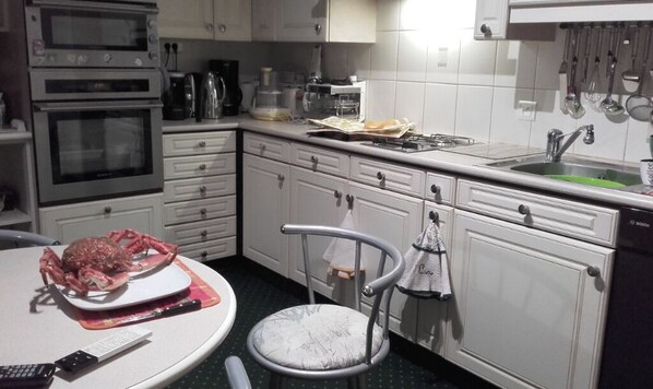 A kitchen with white cabinets, a stove, a sink, and a chair. - Spacious country house in large, secure, enclosed garden. (Sulniac)
