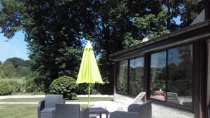 Une terrasse avec des meubles d’extérieur et un grand parasol.