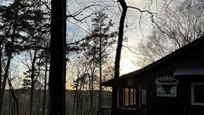 Un chalet rustique doté d’une véranda, entouré d’arbres.