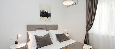 A modern bedroom with a bed, bedside tables, a painting, and a breakfast tray.