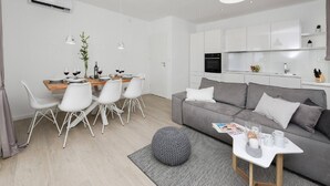 Un espace de vie moderne comprenant un coin repas, un canapé gris et une cuisine.