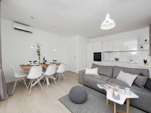 A modern living space with a dining area, a grey sofa, and a kitchen. - Villa in Nin with Stunning Sea Views (Nin)