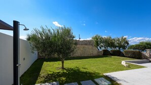 Un espace extérieur bien entretenu, agrémenté d’un muret en pierre, d’un petit arbre et d’un chemin pavé.
