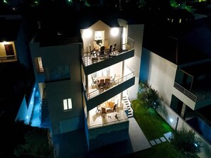 Um edifício com vários andares, com áreas de estar ao ar livre no andar térreo e varandas nos andares superiores.