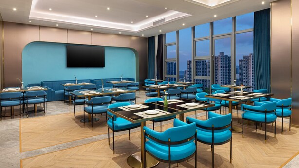 A modern conference room with a city view, blue seating, and a flat-screen TV on the wall. - Ramada BY Wyndham Guangzhou Huangpu (Guangzhou)