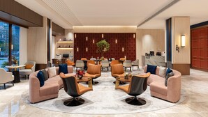 A modern lobby with a central seating area, a reception desk, and a view of the outside. - Ramada BY Wyndham Guangzhou Huangpu (Guangzhou)