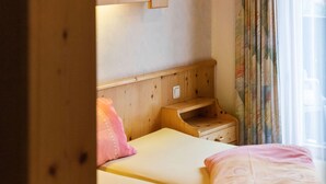 Ein Schlafzimmer mit Holzkopfende, Nachttisch, Fenster mit Vorhängen.