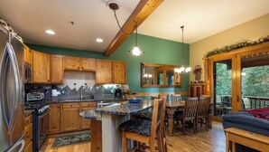 A kitchen with wooden cabinets, a granite countertop, and a dining area with wooden chairs and a table. - Spacious and Bright Keystone Townhome (Keystone)